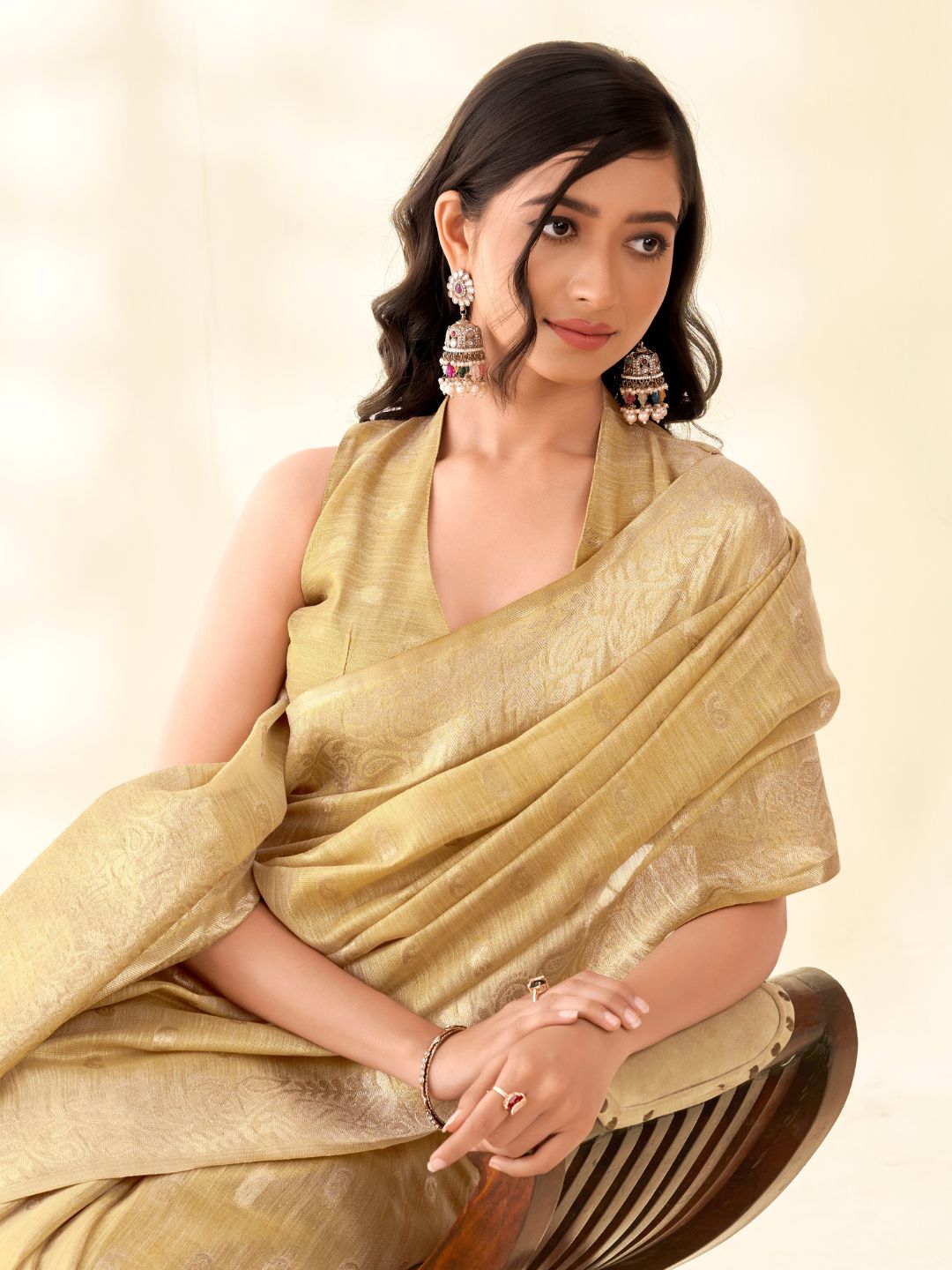 Close portrait of beige tissue linen silk saree highlighting rich zari pallu and fabric texture