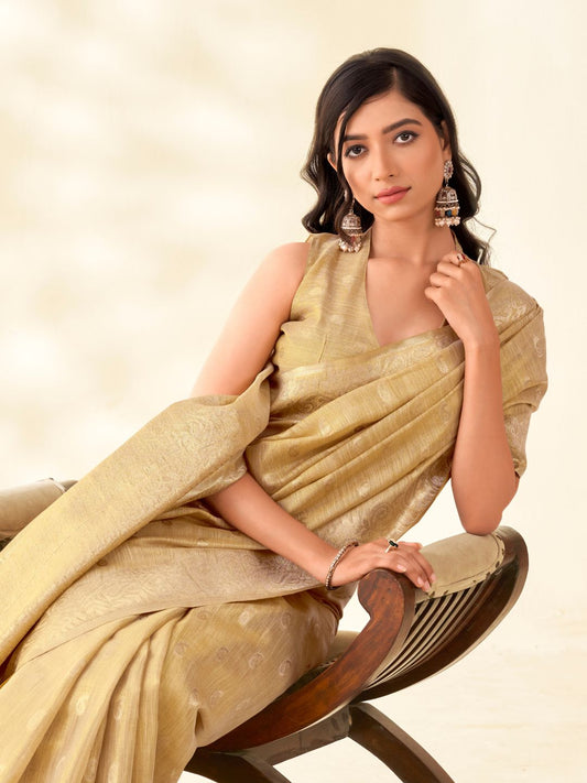 Model sitting in beige tissue linen silk saree with zari butti and pallu showcasing elegant styling