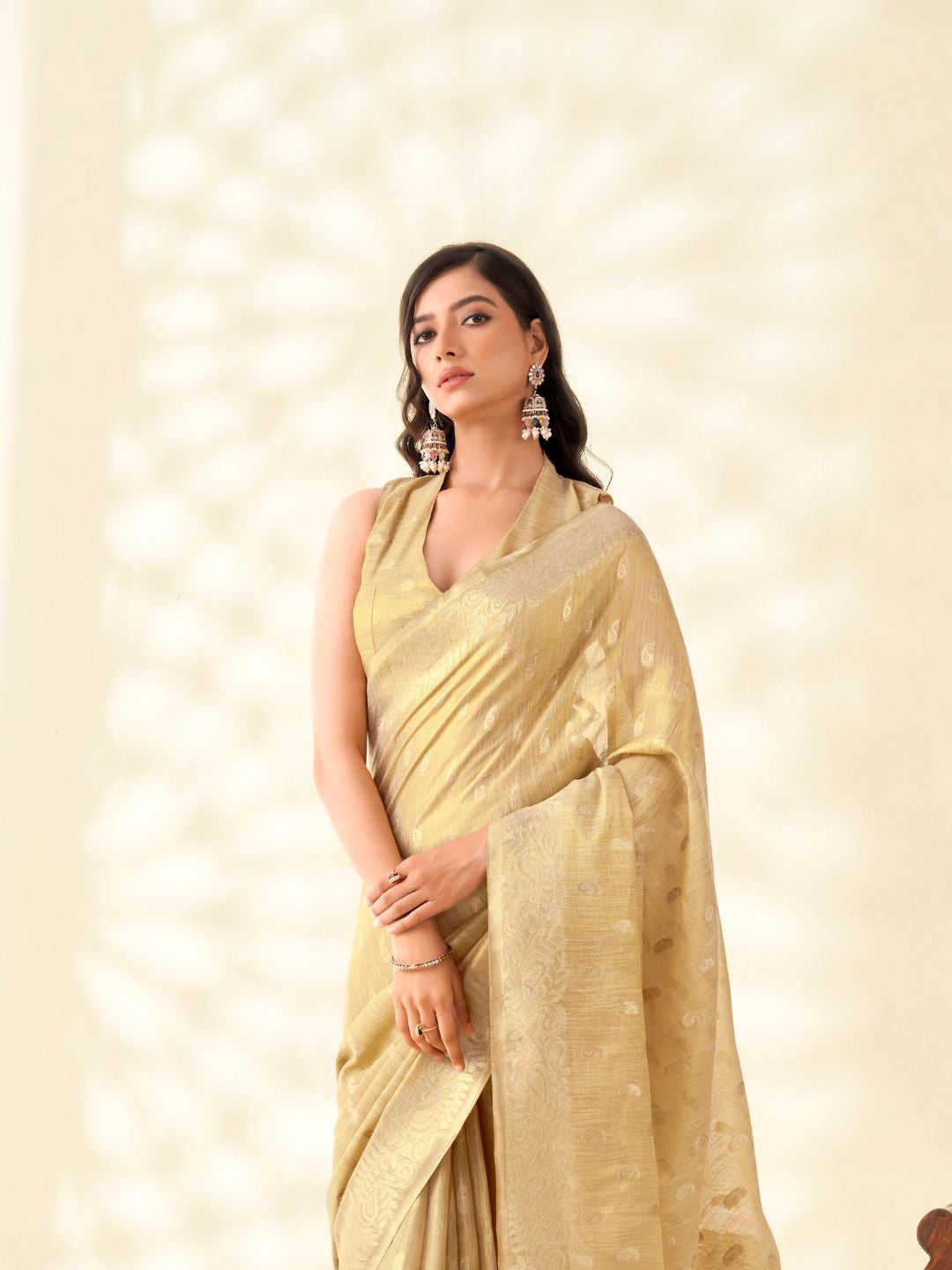 Model posing in beige tissue linen silk saree with zari weaving butti showing full length elegant look