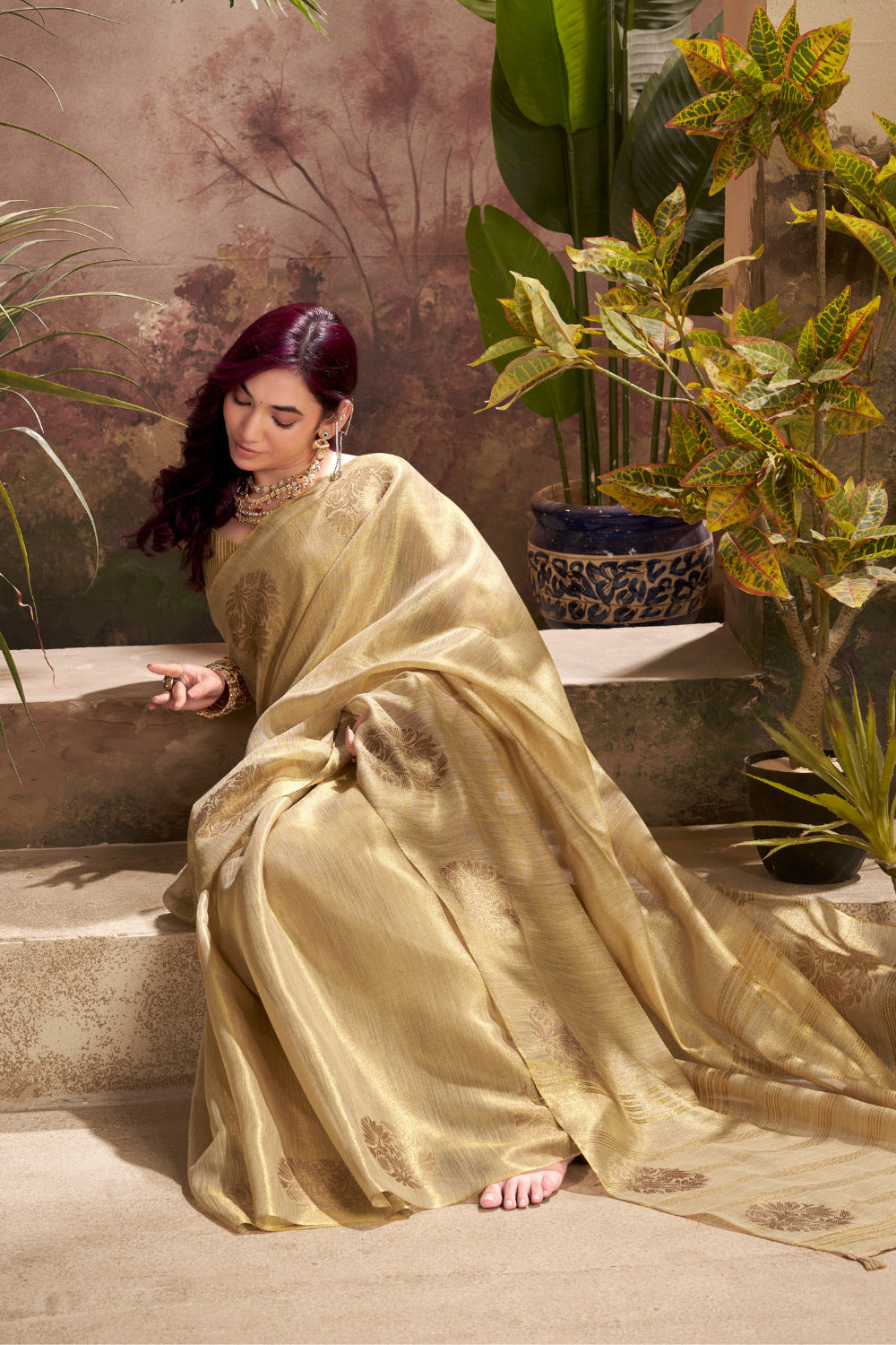 Model sitting in beige tissue silk saree with zari weaving butta highlighting graceful drape and rich texture
