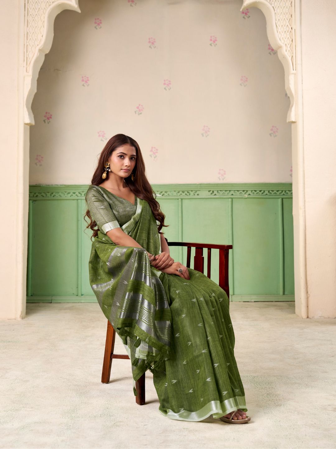 Model posing in green linen silk saree with woven butti design showing full length elegant styling