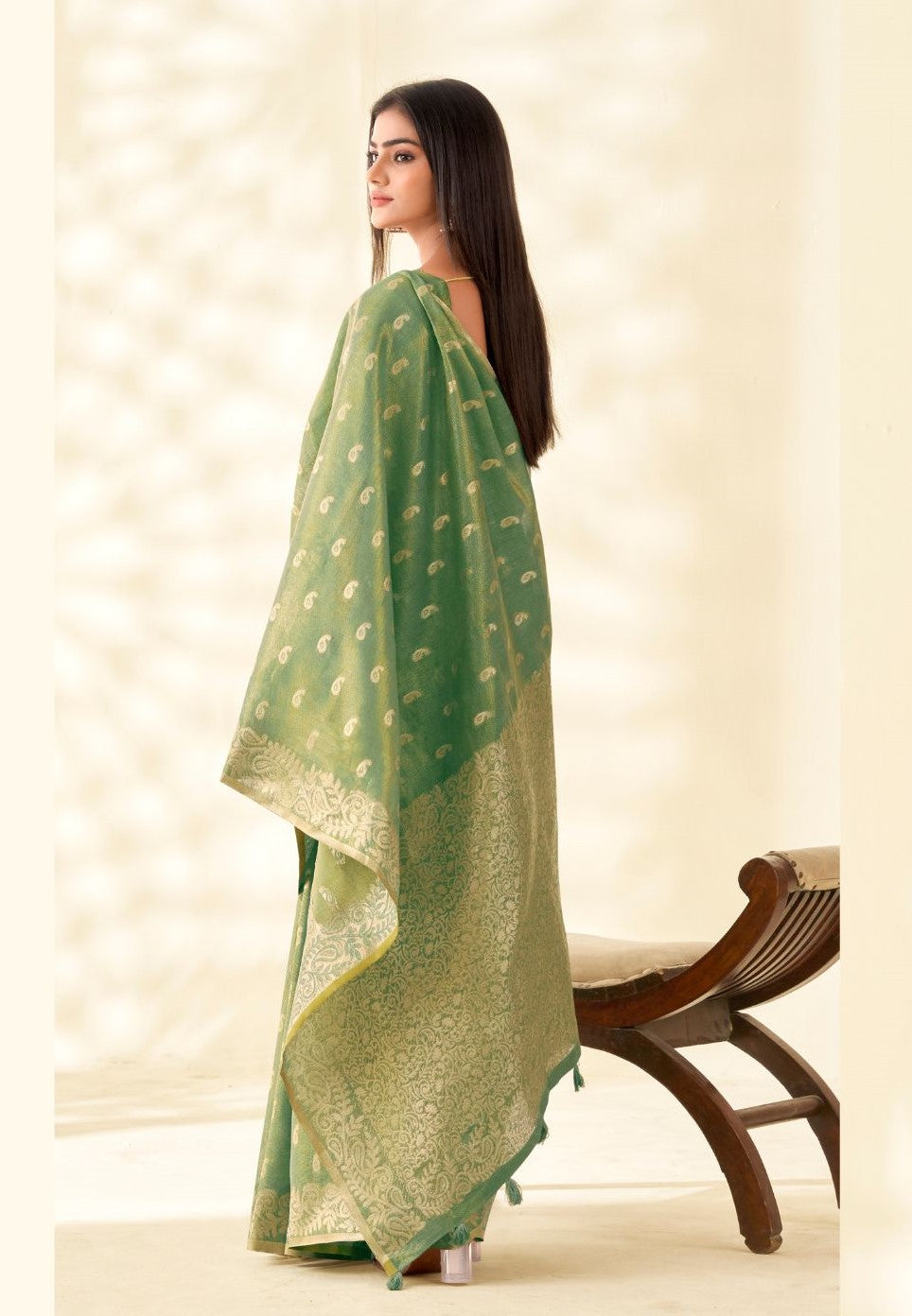 Back view of green tissue linen silk saree showcasing rich zari pallu design and flowing drape