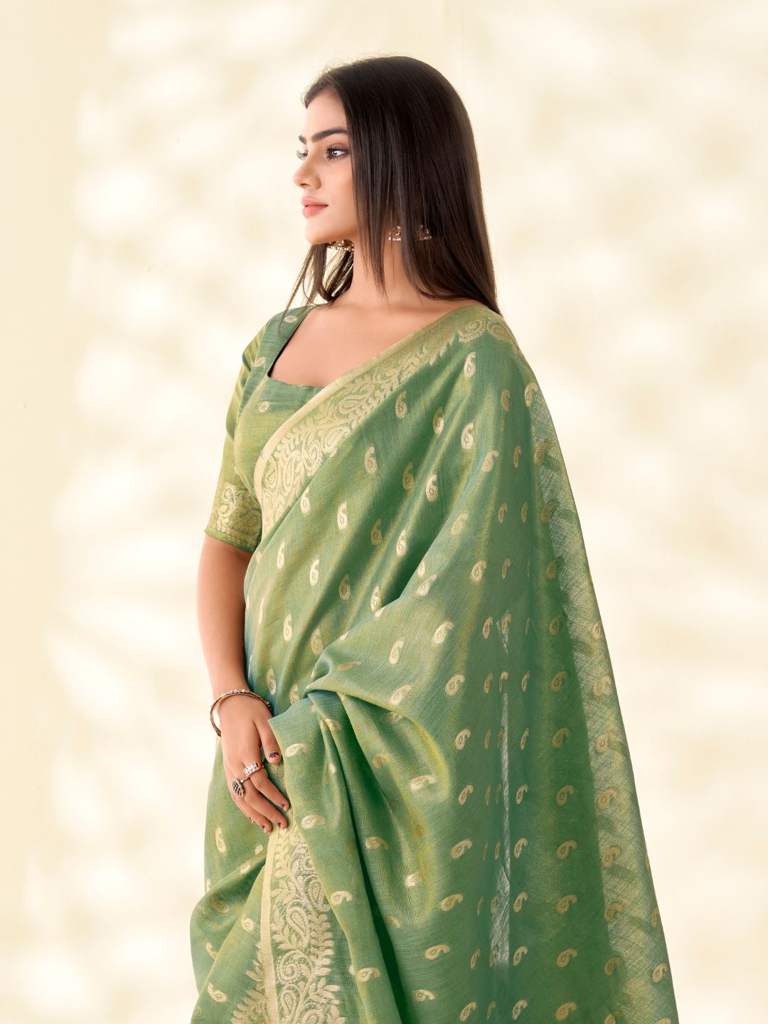 Side view of green tissue linen silk saree highlighting zari weaving butti and graceful drape