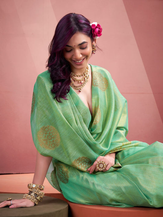Model sitting in green tissue silk saree with zari butta showcasing elegant party wear styling