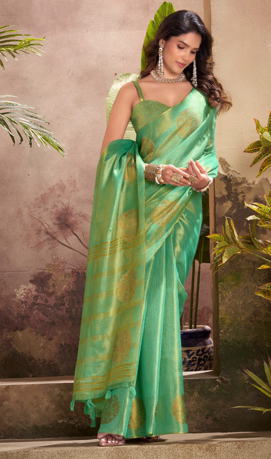 Model posing in green tissue silk saree with zari butta and border pallu showing full length party and wedding styling