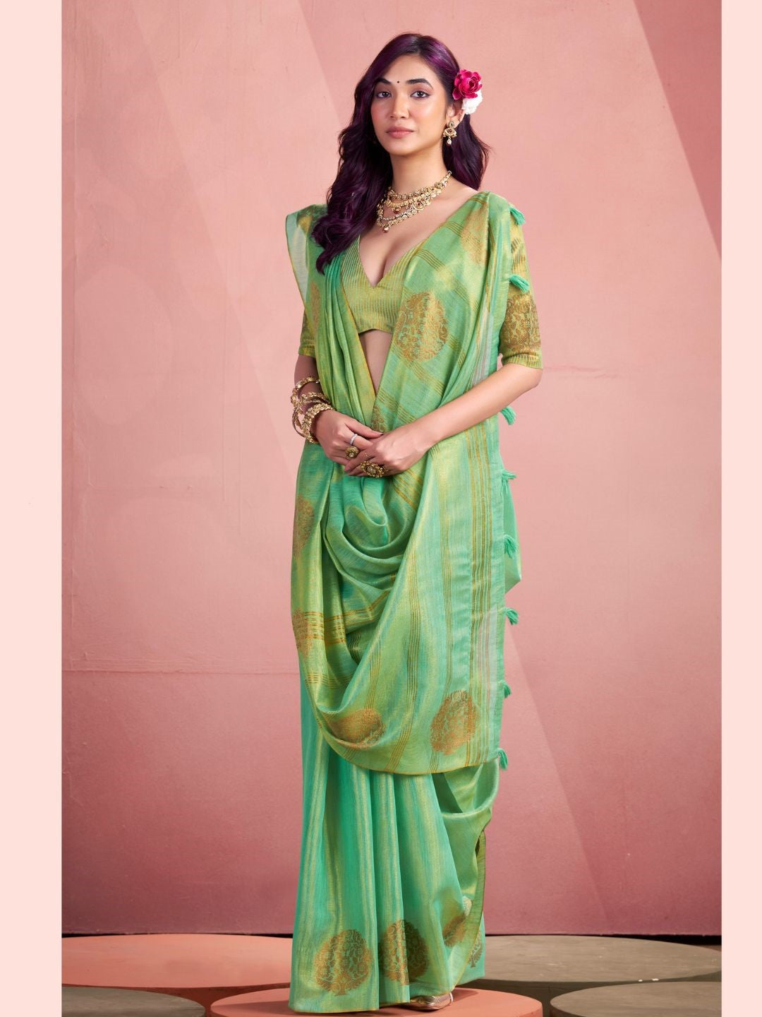 Woman wearing green tissue silk saree with fancy zari weaving butta full front view