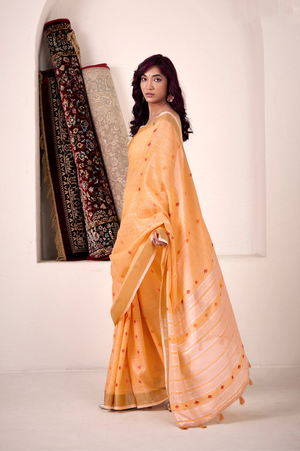 Model posing in orange linen silk saree with zari work showing full length ethnic styling