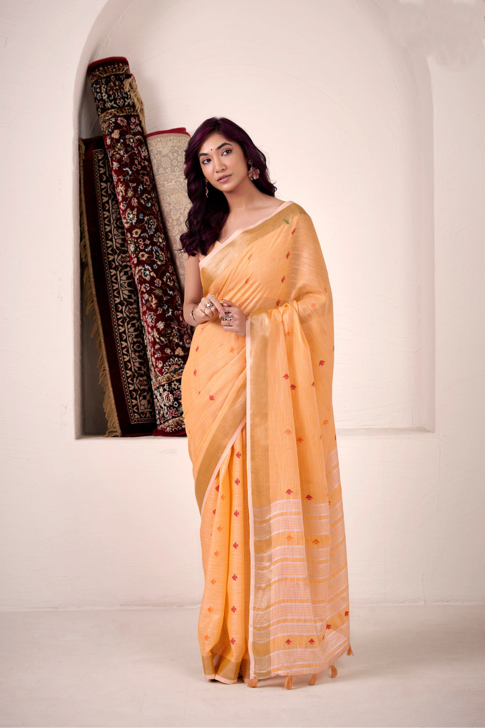 Woman wearing orange soft linen silk saree with zari weaving and elegant lining pallu full view