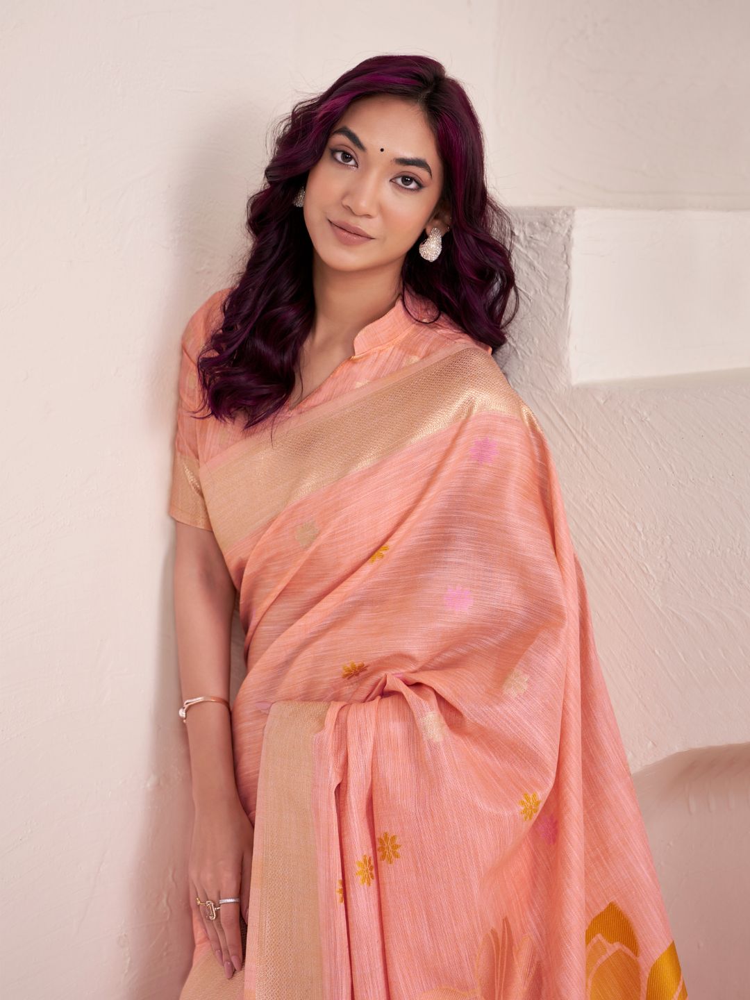 Close view of peach linen silk saree showcasing floral pallu design and soft fabric texture
