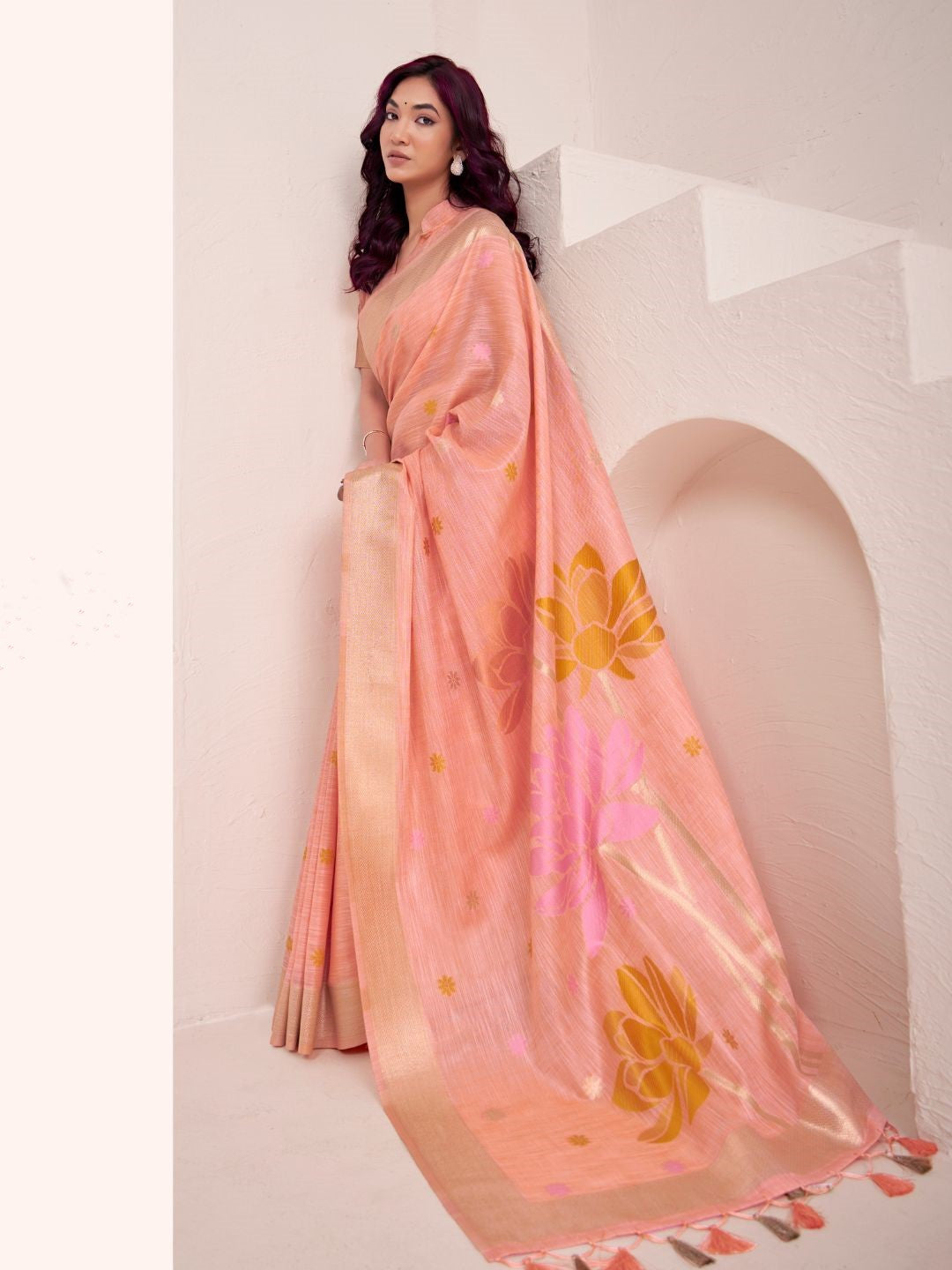 Model posing in peach soft linen silk saree with floral pallu showing full length elegant styling