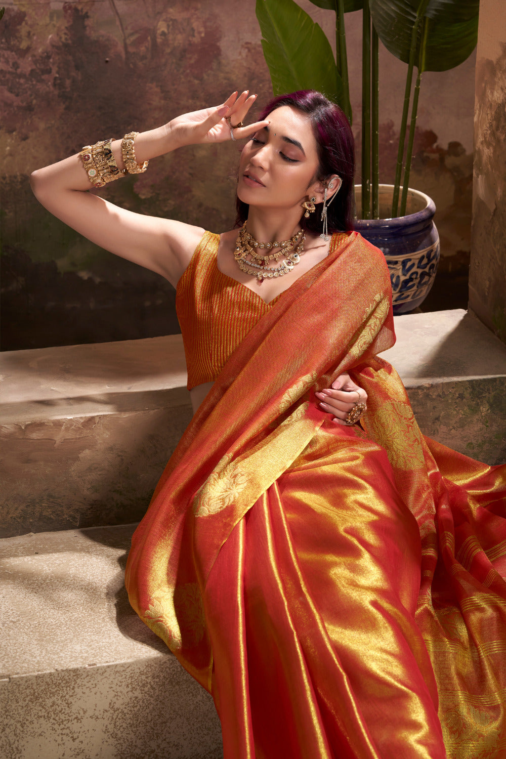Woman posing in red tissue silk saree with zari weaving butta highlighting rich texture and graceful drape