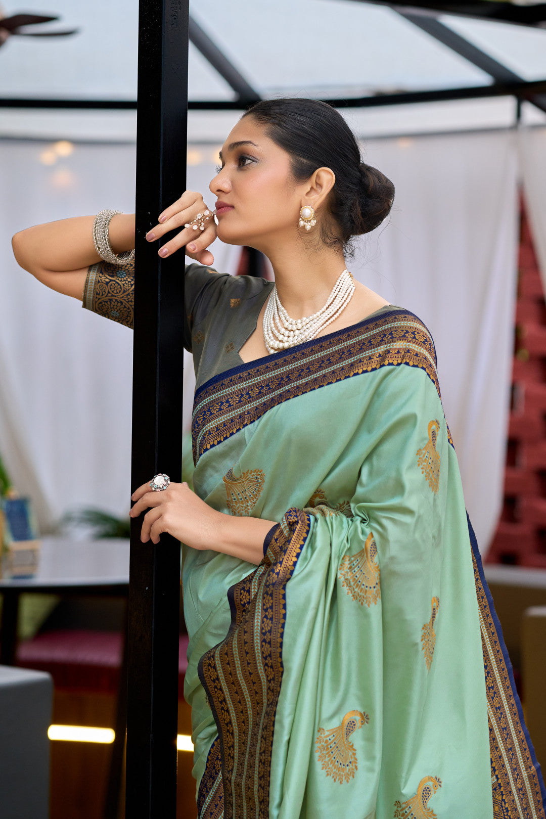 Model wearing sea green Banarasi silk saree with zari weaving and contrast border
